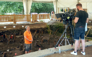 Il responsabile di uno scavo archeologico viene ripreso da un uomo per un'intervista sul luogo dello scavo